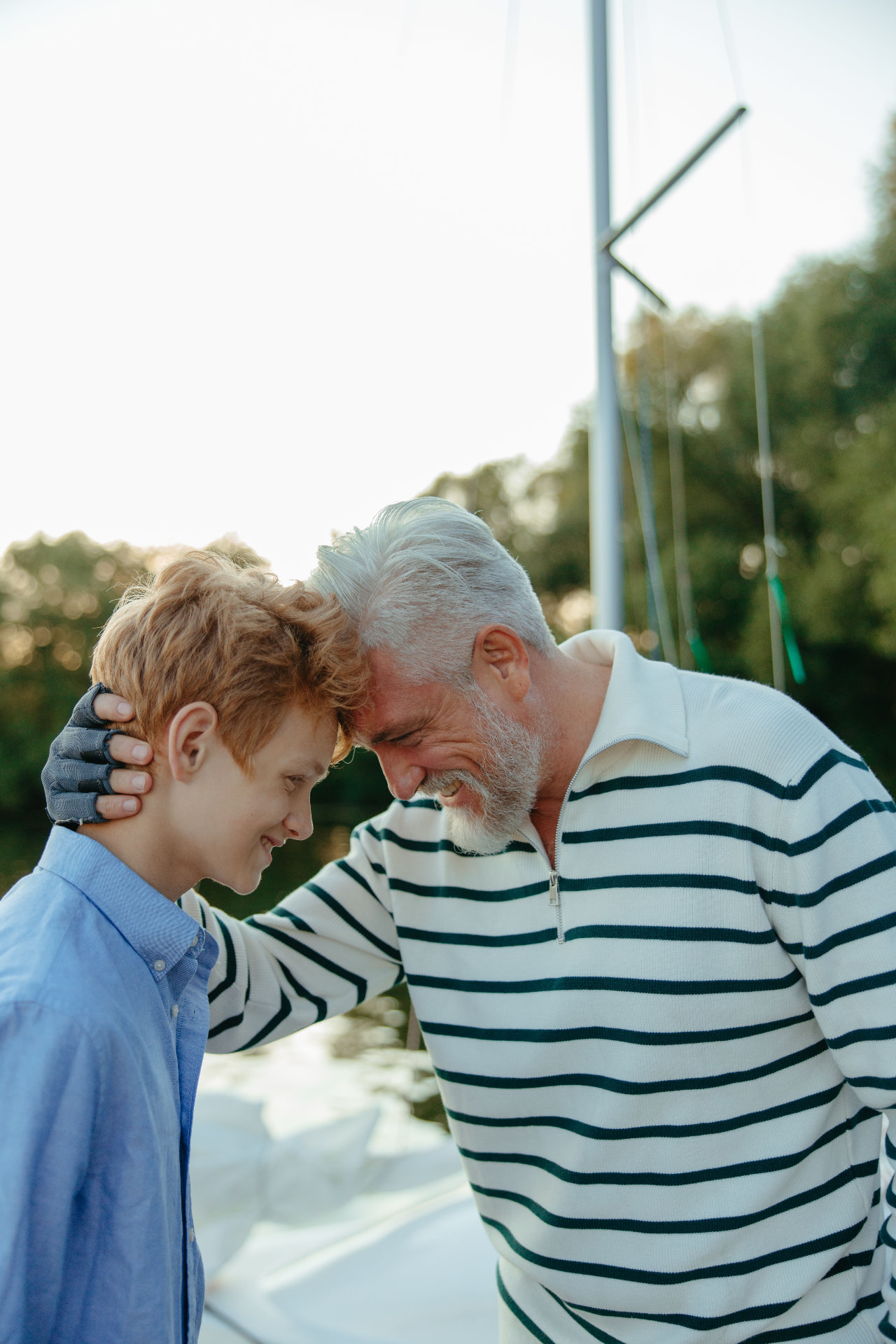 An older man and his grandson sharing a warm moment outdoors by the water
